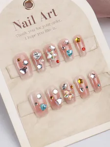 Detail of handmade press-on nails with colorful rhinestones on blush pink jelly base