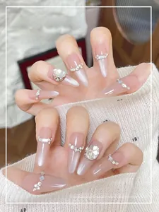 Gros plan d'ongles amande à presser avec paillettes œil-de-chat argentées et gros cristaux