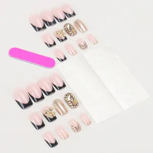 Press-on nail kit with black French tips, glitter accents, and golden 3D bows