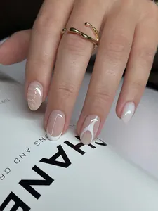 Detailed view of nude pink french press-on nails with white wave patterns and gold ring