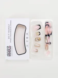 Detail of pink and black French press-on nails with bow and rhinestone decor in packaging