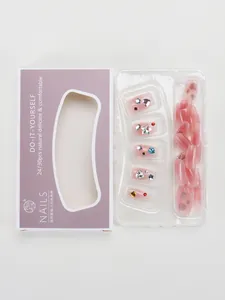 Detail of gradient pink press-on nails with heart and star rhinestones in purple box