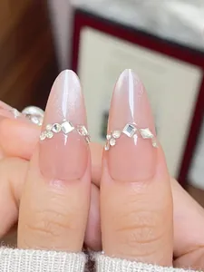Vue macro d'ongles faits main avec paillettes œil de chat, strass et forme d'amande