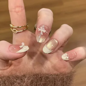 Faux ongles faits main effet œil de chat avec nœuds blancs 3D et dégradé rose nu