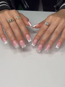 Détails de faux ongles French avec fleurs 3D blanches et décorations de perles élégantes