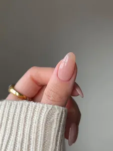 Close-up of translucent nude pink press-on nails with a high-gloss finish and oval shape