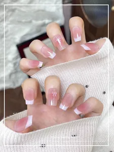 Detail of pink gradient French press-on nails with white butterfly and bow decorations