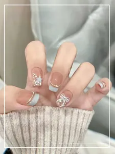 Detailed shot of handmade soft nails with blue french tips, 3D bows, and pearls