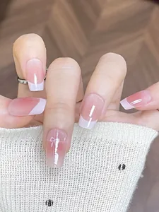 Detail of pink gradient press-on nails with white French tips and bow design