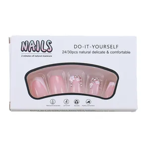 Faux ongles French avec fleurs blanches et strass présentés dans leur boîte d'emballage