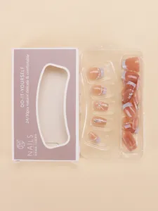 Detail of pink cat-eye press-on nails with bow designs and pearl accents in packaging