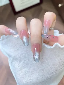 Macro detail of almond gradient nails with pink hearts, rhinestones and lace cuffs