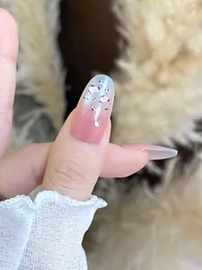 Detailed close-up of pink and blue gradient oval press-on nail with rhinestone and spots