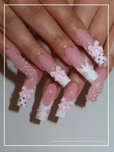 Detail of pink French nails with 3D bows, pearls, and heart patterns on square tips