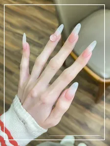 Detail of long almond press-on nails with pink gradient and 3D heart crystal