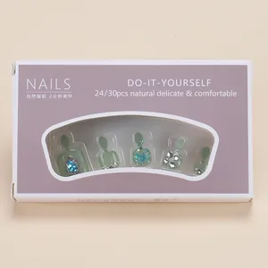 Platliggende set kunstnagels voor tenen in lichtgroen met blauwe strassteentjes en glitter