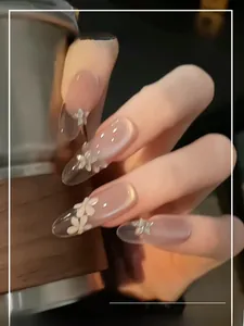 Detailed close-up of nude gradient press-on nails with white 3D flowers and silver butterflies