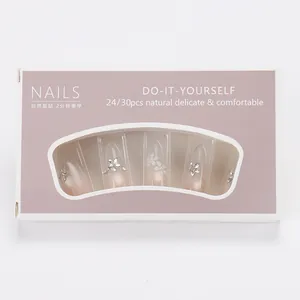 Close-up of pink gradient press-on nails with 3D floral accents and diamond rhinestones