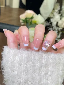 Detail van French press-on nagels met groot hartkristal en strass-steentjes versiering