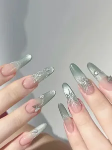 Detailed view of green cat-eye press-on nails with 3D silver butterflies and crystals