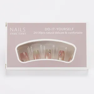 Short blush gradient cat-eye press-on nails set with rhinestones in pink packaging