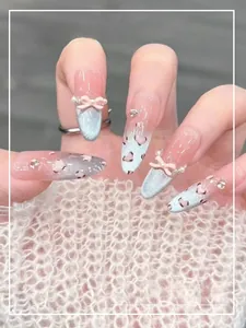 Detail van blauwe cat eye nagels met roze strikjes, parels en handgemaakte hartjes