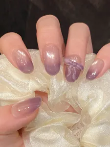 Detail of purple cat eye press-on nails with 3D bow and translucent gradient effect