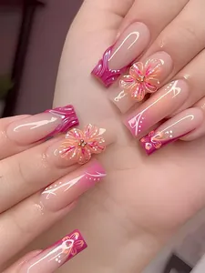 Detail von 3D rosa Blumenanhängern und weißen Mustern auf künstlichen Nägeln mit Farbverlauf