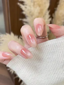 Dettaglio di unghie finte nude cat-eye con sfumatura rosa e finitura lucida extra