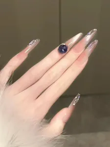 Vue macro d'ongles stiletto longs à coller avec cristaux violets et strass brillants