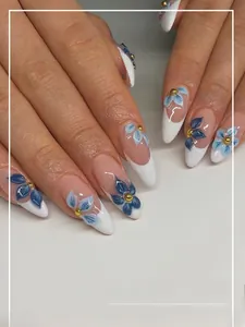 Detail of almond-shaped French press-on nails with blue floral patterns and gold beads