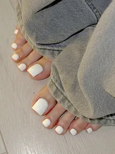 Close-up of glossy pure white square press-on toenails on a natural foot model