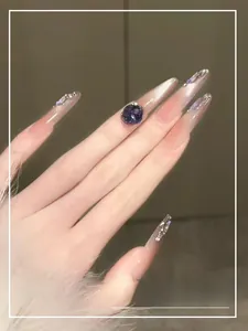 Détail d'ongles en amande douce avec dégradé rose et grand cristal bleu scintillant
