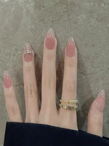 Detail of nude gradient almond press-on nails with silver rhinestones and metal chain