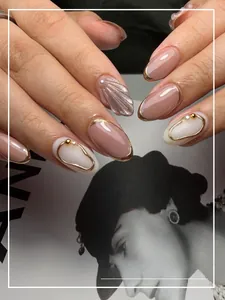 Detailed view of press-on nails featuring pearl white shell texture and golden edge accents