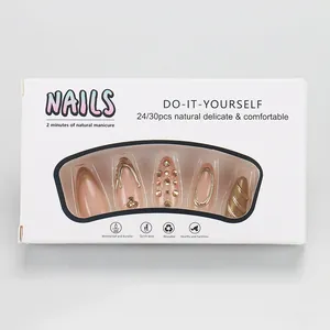 Détail de faux ongles amande avec motifs de vagues 3D dorées et strass brillants
