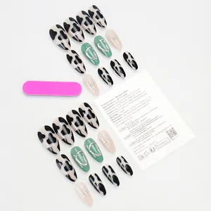 Flat lay of cow print and metallic green press-on nail kit with pink nail file