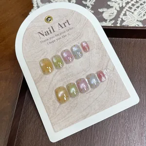 Short square press-on nails with cat-eye effect and orange polka dots on display card