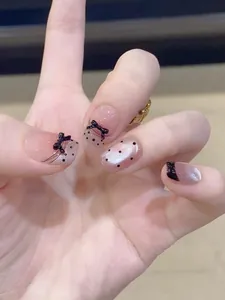 Detailed view of handmade gothic press-on nails with black bows and cat eye glitter finish