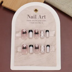 Gothic handmade press-on nails with black polka dots and 3D bows on a display card