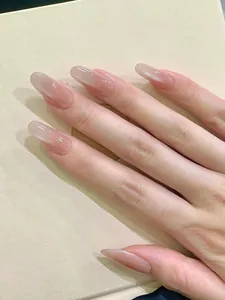 Macro shot of long oval press-on nails with nude pink gradient and cat-eye glitter effect