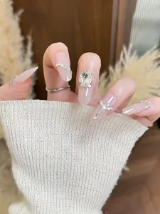 Detail of pink gradient press-on nails with shiny rhinestones and pearls on model