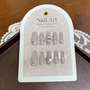 Handmade almond press-on nails in nude pink with luxury rhinestones and chain accents
