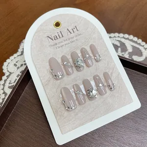 Detailed macro view of handmade pink press-on nails with luxury gems and gold chains