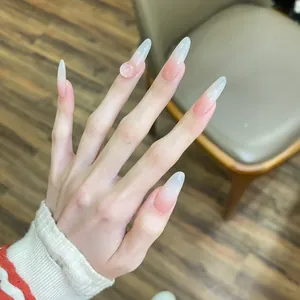 Detail of long almond press-on nails with pink blush gradient and 3D heart jewel