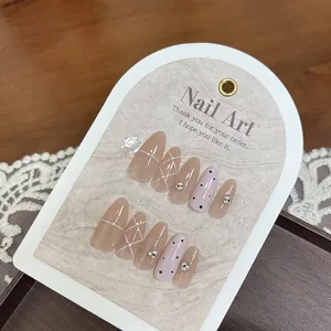 Close-up of almond-shaped press-on nails with plaid patterns, pearls, and rhinestones