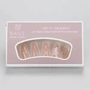 Detail of almond-shaped press-on nails with pearls and diamond accents in purple packaging