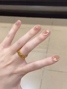 Detail showing a gold lava-textured ring paired with star-themed handmade press-on nails