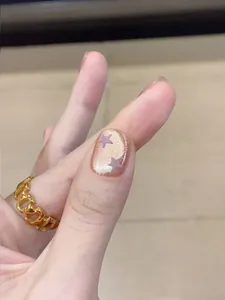Detail of star-patterned cat-eye nails with shimmering purple beads and golden ring