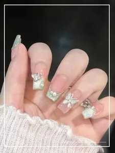 Macro shot of light green cat eye nails with 3D rhinestones and pearl butterflies